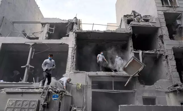 Volunteers clean debris from a residential building damaged when a nearby police station was hit Friday in a U.S.-Israeli strike in Tehran, Iran, Sunday, March 15, 2026. (AP Photo/Vahid Salemi)
