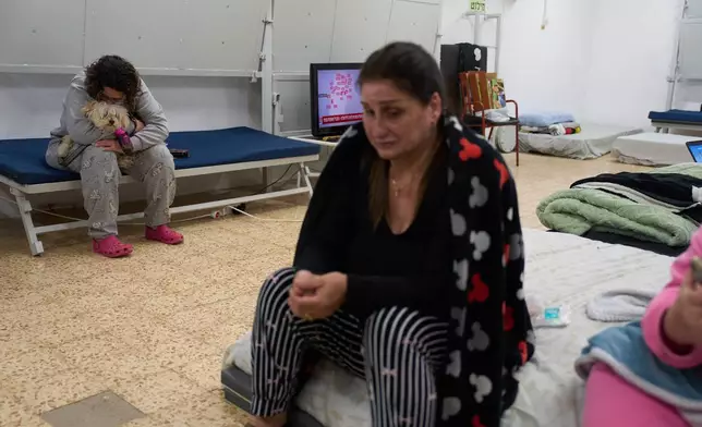 Nofar Eliash holds her dog as she takes shelter with others while air raid sirens warn of incoming Iranian and Hezbollah missile strikes in Kiryat Shmona, northern Israel, Monday, March 16, 2026. (AP Photo/Ariel Schalit)