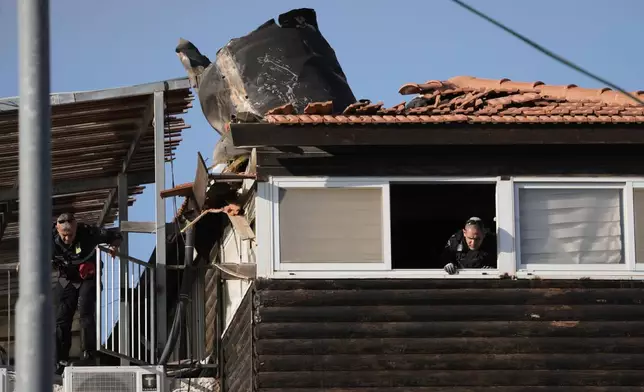 Israeli security forces inspect a house in east Jerusalem where a fragment of an Iranian missile crashed onto the rooftop, Monday, March 16, 2026. (AP Photo/Mahmoud Illean)