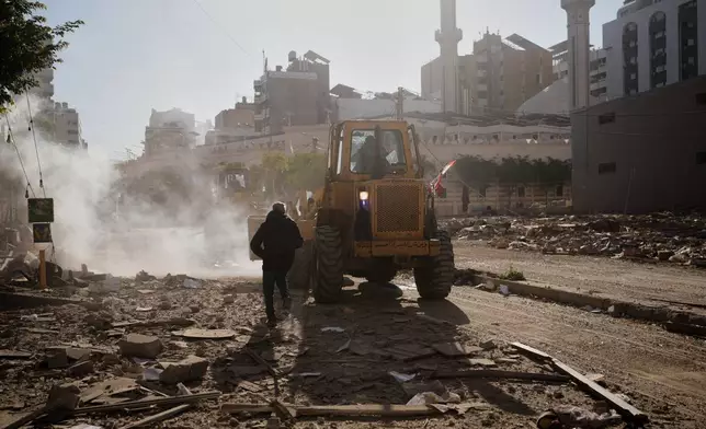 A man runs past a bulldozer clearing debris from a building damaged in an Israeli airstrike in Dahiyeh, Beirut's southern suburbs, Lebanon, Tuesday, March 17, 2026. (AP Photo/Hassan Ammar)