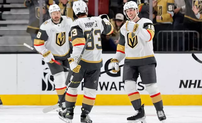 Vegas Golden Knights right wing Pavel Dorofeyev, right, celebrates with right wing Mitch Marner (93) after scoring against the Chicago Blackhawks during the first period of an NHL hockey game Saturday, March 14, 2026, in Las Vegas. Vegas Golden Knights center Tomas Hertl (48) looks on at left. (AP Photo/Steve Marcus)