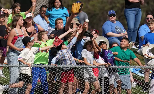 Fans reach for a baseball tossed into the crowd by Los Angeles Angels center fielder Mike Trout during the fourth inning of a spring training baseball game against the San Diego Padres Tuesday, March 10, 2026, in Tempe, Ariz. (AP Photo/Ross D. Franklin)