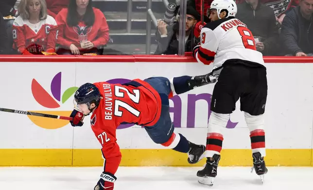 New Jersey Devils defenseman Johnathan Kovacevic (8) hits Washington Capitals right wing Anthony Beauvillier (72) during the first period of an NHL hockey game Friday, March 20, 2026, in Washington. (AP Photo/Nick Wass)