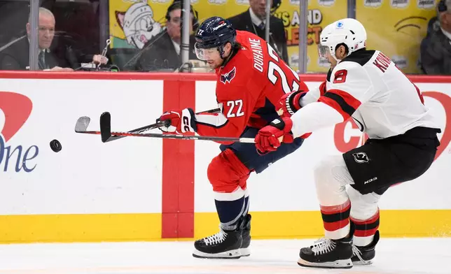 Washington Capitals left wing Brandon Duhaime (22) and New Jersey Devils defenseman Johnathan Kovacevic (8) chase the puck during the second period of an NHL hockey game Friday, March 20, 2026, in Washington. (AP Photo/Nick Wass)