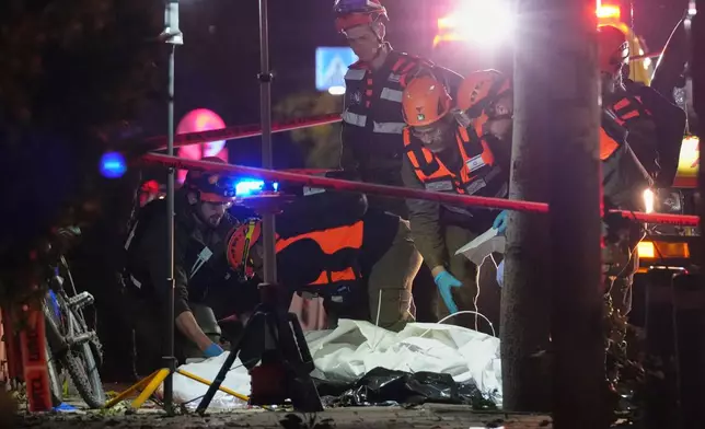 Israeli first responders remove the body of a person from the site of a missile strike in Tel Aviv, Israel, early Saturday, March 28, 2026. (AP Photo/Maya Levin)