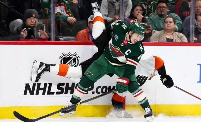 Minnesota Wild defenseman Jared Spurgeon, front, upends Philadelphia Flyers right wing Nikita Grebenkin, behind, during the second period of an NHL hockey game, Thursday, March 12, 2026, in St. Paul, Minn. (AP Photo/Ellen Schmidt)