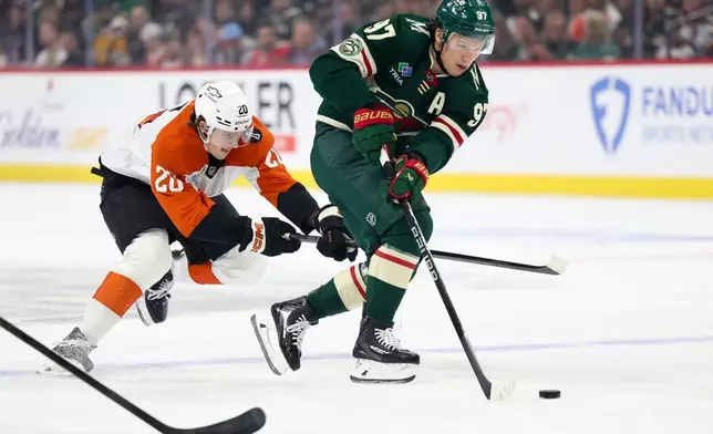 Minnesota Wild left wing Kirill Kaprizov (97) takes the puck up the ice while Philadelphia Flyers left wing Alex Bump (20) defends during the first period of an NHL hockey game Thursday, March 12, 2026, in St. Paul, Minn. (AP Photo/Ellen Schmidt)
