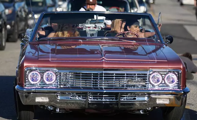 Sandy Avila, right, drives her 1966 Chevy Impala SS at the 6th Annual Lady Lowrider Cruise Night in celebration of International Women's Day in Pasadena, Calif., on Sunday, March 8, 2026. (AP Photo/Damian Dovarganes)