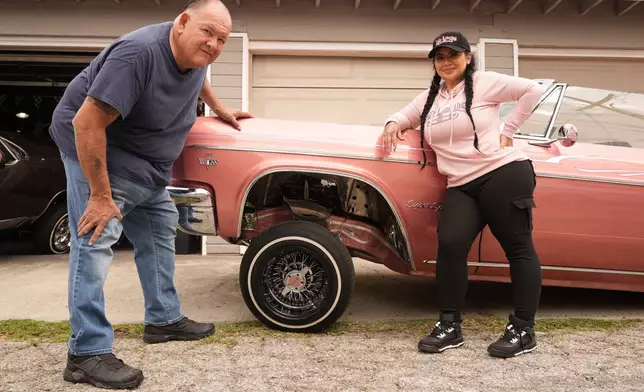 Freehand and pinstriping artist Danny Alvarado, left, and customer Sandy Avila, pose with her 1966 Chevy Impala, at his in Monrovia, Calif., Tuesday, March 10, 2026. (AP Photo/Damian Dovarganes)