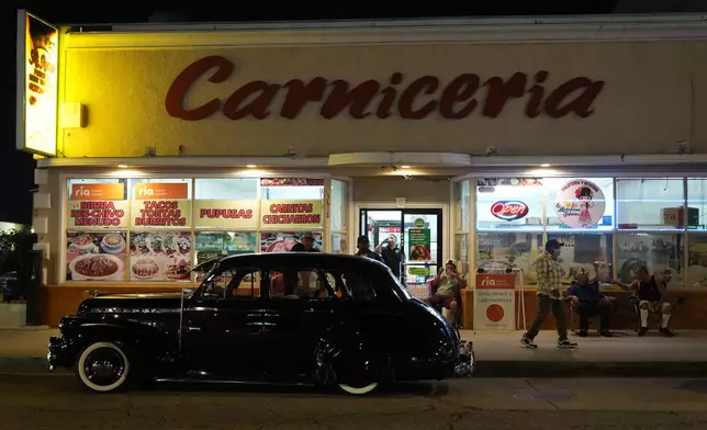 A vintage lowrider is parked in front of a butcher's shop at the 6th Annual Lady Lowrider Cruise Night in celebration of International Women's Day in Pasadena, Calif., on Sunday, March 8, 2026. (AP Photo/Damian Dovarganes)