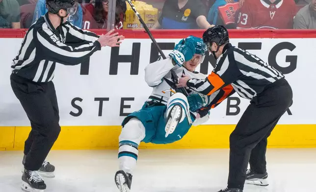 San Jose Sharks' Igor Chernyshov (92) falls to the ice as he tries to stand following a check by Montreal Canadiens' Mike Matheson (not shown) as referee Eric Furlatt (right) helps during the first period of an NHL hockey game in Montreal, Saturday, March 14, 2026. (Christinne Muschi/The Canadian Press via AP)