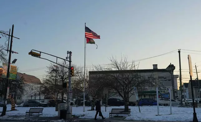 A man walks near flags of the United States and Palestine as the sun sets in "Palestine Way," a section of Main Street in Paterson, N.J. during Ramadan on Friday, Feb. 27, 2026. (AP Photo/Luis Andres Henao)