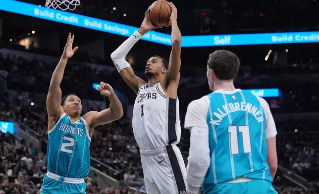 San Antonio Spurs forward Victor Wembanyama (1) drives to the basket against Charlotte Hornets forward Grant Williams (2) during the first half of an NBA basketball game in San Antonio, Saturday, March 14, 2026. (AP Photo/Eric Gay)