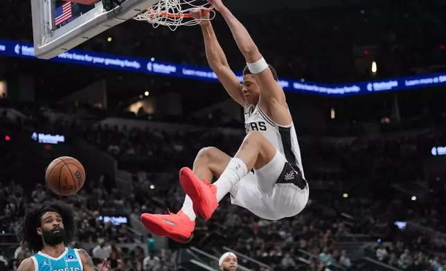 San Antonio Spurs forward Carter Bryant (11) scores over Charlotte Hornets guard Coby White (3) during the first half of an NBA basketball game in San Antonio, Saturday, March 14, 2026. (AP Photo/Eric Gay)