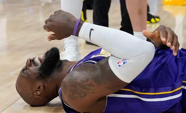 Los Angeles Lakers' LeBron James reaches for his elbow after hitting court while being fouled by Houston Rockets' Jabari Smith Jr. during the second half of an NBA basketball game Wednesday, March 18, 2026, in Houston. (AP Photo/David J. Phillip)