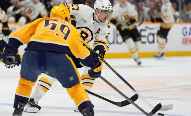 Boston Bruins defenseman Hampus Lindholm (27) skates the puck against Nashville Predators defenseman Roman Josi (59) during the first period of an NHL hockey game Thursday, March 5, 2026, in Nashville, Tenn. (AP Photo/George Walker IV)