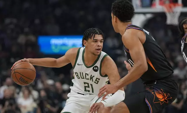 Milwaukee Bucks forward Ousmane Dieng (21) shields the ball from Phoenix Suns forward Oso Ighodaro during the first half of an NBA basketball game, Saturday, March 21, 2026, in Phoenix. (AP Photo/Rick Scuteri)