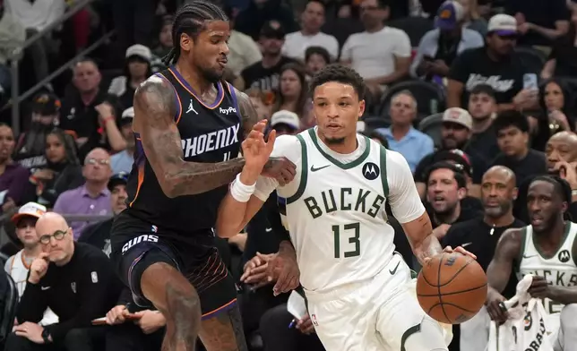 Milwaukee Bucks guard Ryan Rollins (13) drives on Phoenix Suns guard Jalen Green during the first half of an NBA basketball game, Saturday, March 21, 2026, in Phoenix. (AP Photo/Rick Scuteri)