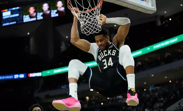 Milwaukee Bucks' Giannis Antetokounmpo hangs on the rim after dunking during the second half of an NBA basketball game against the Indiana Pacers, Sunday, March 15, 2026, in Milwaukee. (AP Photo/Aaron Gash)