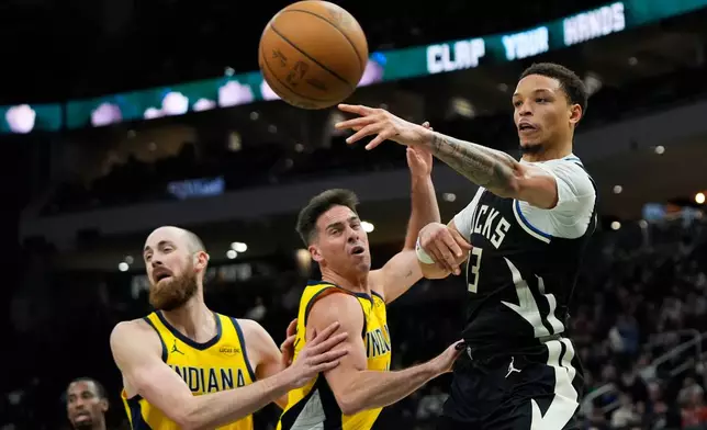Milwaukee Bucks' Ryan Rollins, right, passes around Indiana Pacers' T.J. McConnell, center, and Jay Huff during the second half of an NBA basketball game, Sunday, March 15, 2026, in Milwaukee. (AP Photo/Aaron Gash)