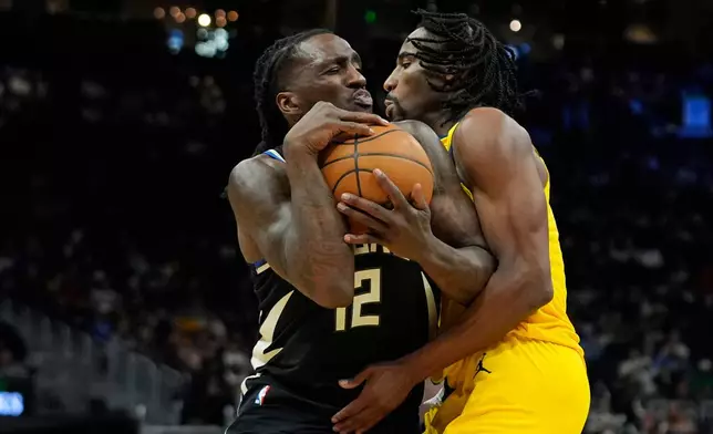 Milwaukee Bucks' Taurean Prince (12) drives to the basket against Indiana Pacers' Aaron Nesmith, right, during the second half of an NBA basketball game, Sunday, March 15, 2026, in Milwaukee. (AP Photo/Aaron Gash)