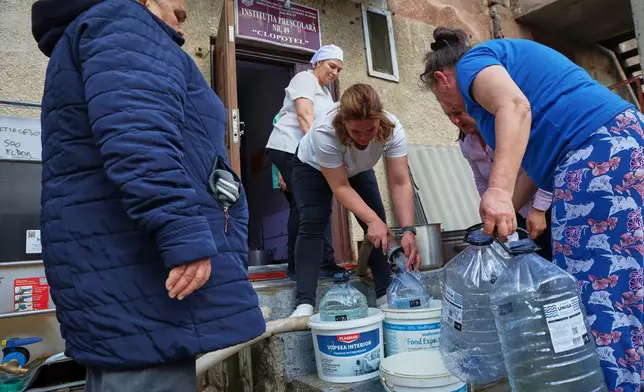 People fill containers with drinking water distributed by the emergency services in Balti, Moldova, Tuesday, March 17, 2026. (AP Photo/Aurel Obreja)