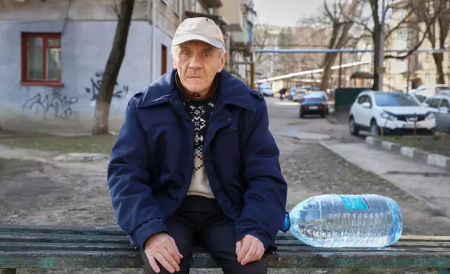 Valentin Belischii, 73 years-old, pauses on a bench before climbing the stairs to his fourth floor apartment with a container of water he bought in Balti, Moldova, Tuesday, March 17, 2026. (AP Photo/Aurel Obreja)