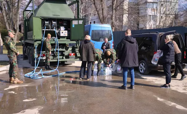 People fill containers with non-potable water distributed by the emergency services in Balti, Moldova, Tuesday, March 17, 2026. (AP Photo/Aurel Obreja)