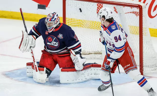 New York Rangers' Gabe Perreault (94) looks on as Adam Fox's (not shown) shot gets past Winnipeg Jets goaltender Connor Hellebuyck (37) during the first period of an NHL game in Winnipeg, Thursday, March 12, 2026. (John Woods/The Canadian Press via AP)