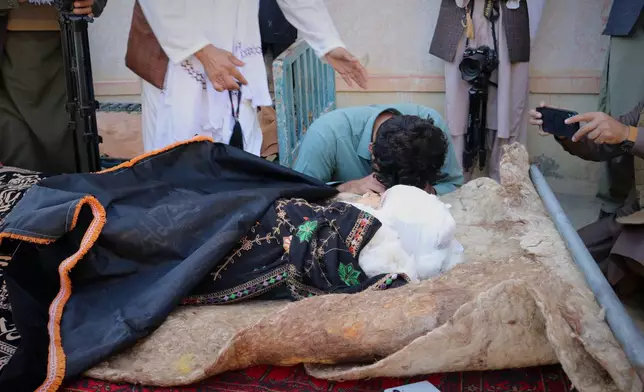A man mourns next to the body of a child killed in a strike that hit a house in the Momand Dara district of Nangarhar province, Afghanistan, near the border with Pakistan, Friday, March 13, 2026. (AP Photo/Hedayat Shah)