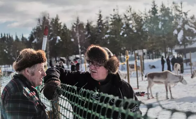 Reindeer herders Kalevi Simontaival, left, and Juhani Mantyranta, right, chat at the fence during the Salla Porocup reindeer sprint racing event, in Salla, Finland, March 7, 2026. (AP Photo/Aino Vaananen)
