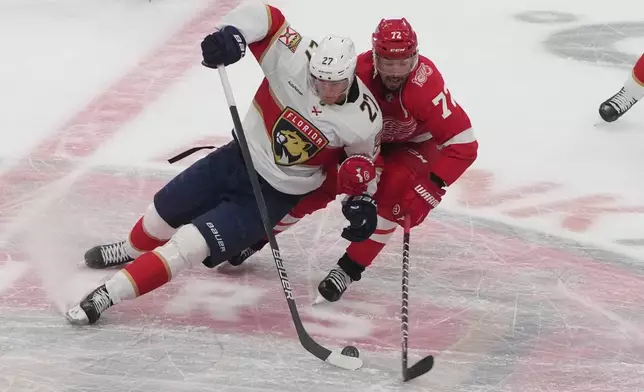 Florida Panthers center Eetu Luostarinen (27) and Detroit Red Wings defenseman Justin Faulk (72) go after the puck during the second period of an NHL hockey game, Tuesday, March 10, 2026, in Sunrise, Fla. (AP Photo/Marta Lavandier)