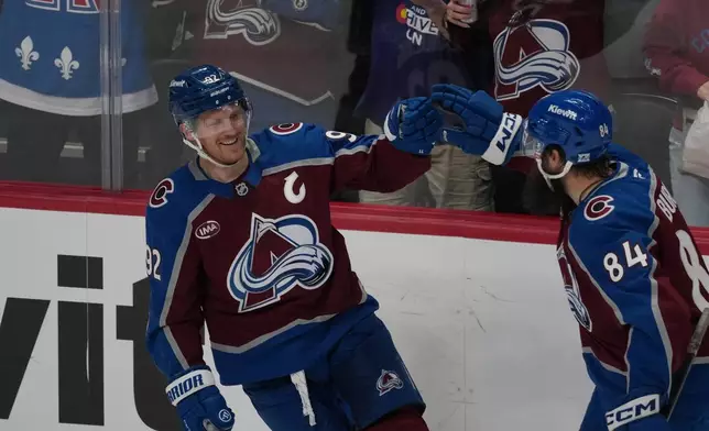 Colorado Avalanche defenseman Brent Burns, right, congratulates left wing Gabriel Landeskog after his goal against the Calgary Flames in the first period of an NHL hockey game Monday, March 30, 2026, in Denver. (AP Photo/David Zalubowski)