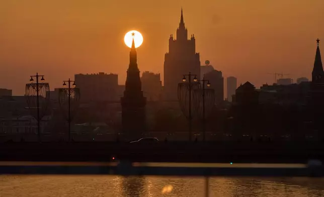 The sun is seen behind a Red Star atop of a Kremlin Tower during sunset in Moscow, Thursday, March 12, 2026, backdropped by a Stalin's style skyscraper. (AP Photo/Alexander Zemlianichenko)