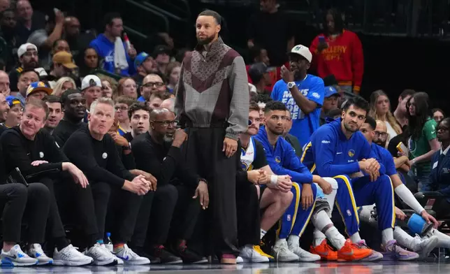 Golden State Warriors guard Stephen Curry looks on from the bench during the second half of an NBA basketball game against the Dallas Mavericks Monday, March 23, 2026, in Dallas. (AP Photo/Julio Cortez)