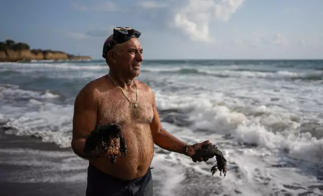Fisherman Leopoldo Salgado holds clumps of oil residue collected along the shore days after an oil spill in the Gulf of Mexico that authorities said originated from an unidentified vessel and two natural oil seeps in Salinas, Mexico, Thursday, March 26, 2026. (AP Photo/Felix Marquez)