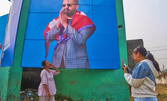 A Rastriya Swatantra Party supporter photographs a friend in front of a large banner depicting party leader Balendra Shah during an election rally in Chitwan, approximately 180 kilometers (112 miles) west of Kathmandu, Nepal, Friday, Feb. 27, 2026. (AP Photo/Niranjan Shrestha)