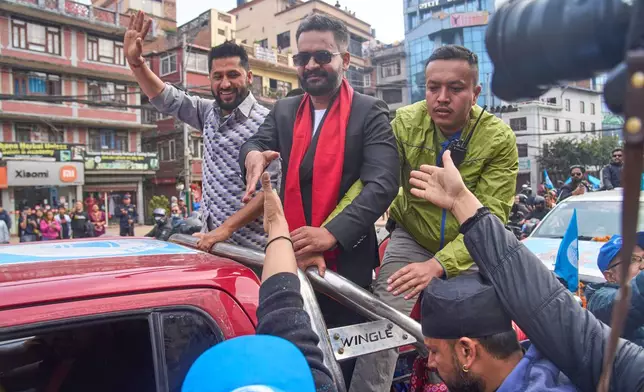 Balendra Shah, right, former mayor of Kathmandu Metropolitan City and prime ministerial candidate of the Rastriya Swatantra Party, center, greets people during a road show ahead of national election in Lalitpur, Nepal, Saturday, Feb. 28, 2026. (AP Photo/Niranjan Shrestha)