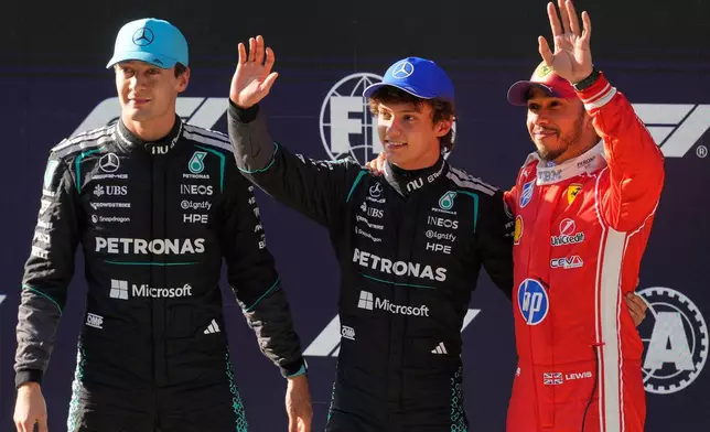 Mercedes driver Andrea Kimi Antonelli of Italy, center, waves after getting the pole position beside Mercedes driver George Russell, left, of Britain and Ferrari driver Lewis Hamilton of Britain during the qualifying session of the Chinese Formula One Grand Prix at the Shanghai International Circuit, in Shanghai, China, Saturday, March 14, 2026. (AP Photo/Vincent Thian)