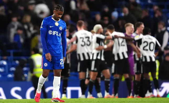 Chelsea's Jorrel Hato looks dejected as Newcastle United players celebrate victory following the Premier League match between Chelsea and Newcastle, in London, Saturday March 14, 2026. (John Walton/PA via AP)