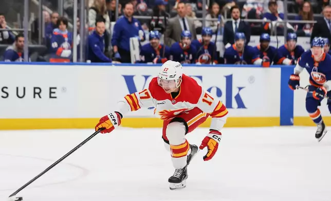 Calgary Flames center Yegor Sharangovich (17) reaches for the puck during the first period of an NHL hockey game against the New York Islanders, Saturday, March 14, 2026, in Elmont, N.Y. (AP Photo/Heather Khalifa)