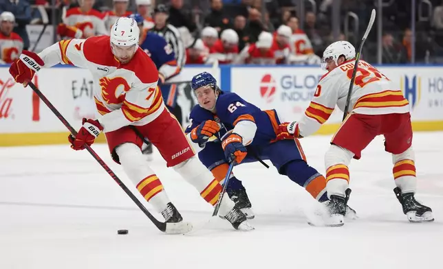 Calgary Flames defenseman Kevin Bahl (7) keeps the puck away from New York Islanders center Calum Ritchie (64) during the second period of an NHL hockey game, Saturday, March 14, 2026, in Elmont, N.Y. (AP Photo/Heather Khalifa)