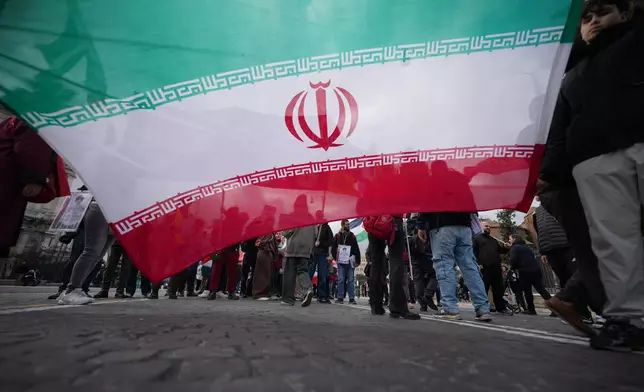 Protesters hold an Iranian flag as they take part in a national demonstration against the war in Iran and the March 22 referendum on the Italian justice system, in Rome, Saturday, March 14 2026. (AP Photo/Andrew Medichini)