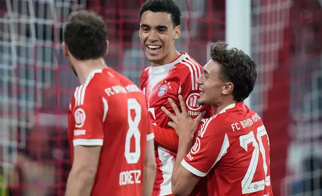 Bayern's Jamal Musiala, left, celebrates with team mate Tom Bischof after scoring from the penalty spot his side's third goal during the Bundesliga soccer match between FC Bayern Munich and Borussia Moenchengladbach in Munich, Germany, March 6, 2026. (AP Photo/Matthias Schrader)