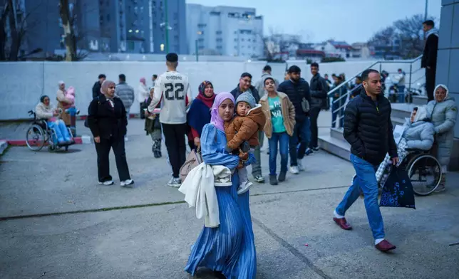 A woman holding a baby arrives for Eid al-Fitr prayers outside a sports hall in Bucharest, Romania, Friday, March 20, 2026. (AP Photo/Vadim Ghirda)