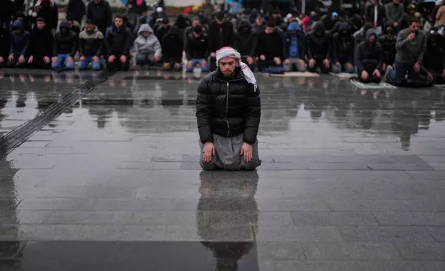 Muslim worshippers attend Eid al-Fitr prayers outside a mosque in Istanbul, Friday, March 20, 2026. (AP Photo/Khalil Hamra)