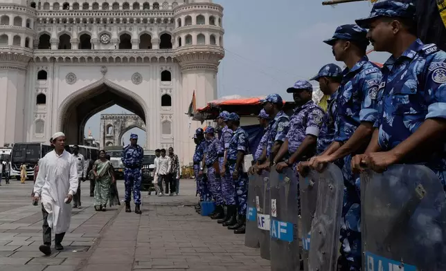 A Muslim walks toward Mecca Masjid to offer prayers on the last Friday of the holy fasting month of Ramadan as Rapid Action Force personnel stand guard in front of the Charminar monument in Hyderabad, India, Friday, March 20, 2026. (AP Photo/Mahesh Kumar A.)
