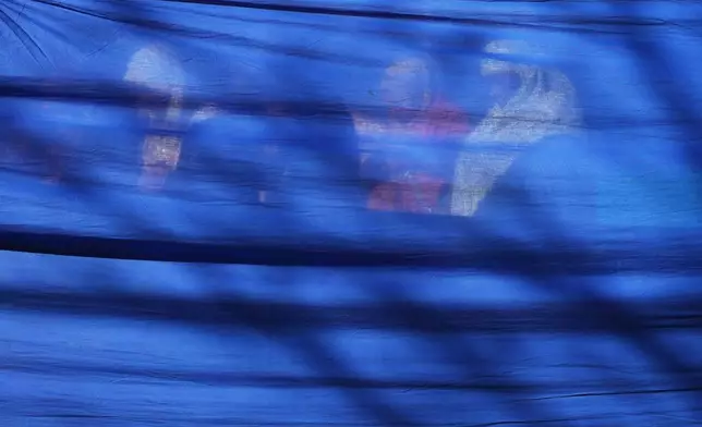 Women pray behind a curtain during Eid al-Fitr, the Muslim holiday marking the end of Ramadan, Islam's holy month of fasting, in Rome's Piazza Vittorio, Friday, March 20, 2026. (AP Photo/Alessandra Tarantino)