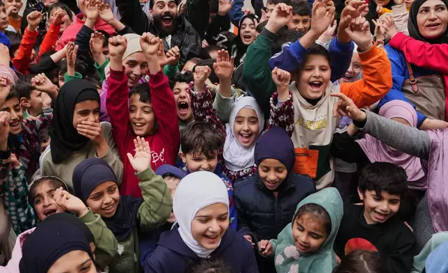 Children cheer as volunteers prepare food parcels and Eid sweets for displaced families living in a public university turned into a shelter after Israeli airstrikes in Beirut, Lebanon, Friday, March 20, 2026. (AP Photo/Hassan Ammar)