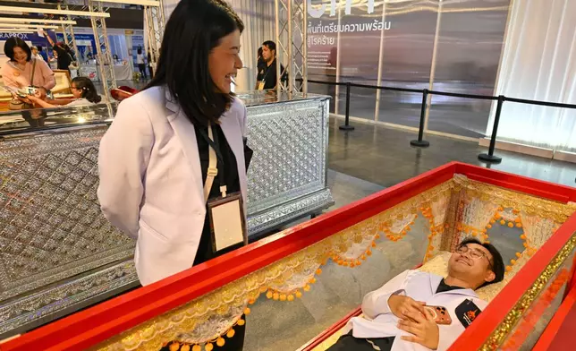 A visitor tries out a coffin at Death Fest in Nonthaburi, Thailand, Friday, March 13, 2026. (AP Photo/Kittinun Rodsupan)